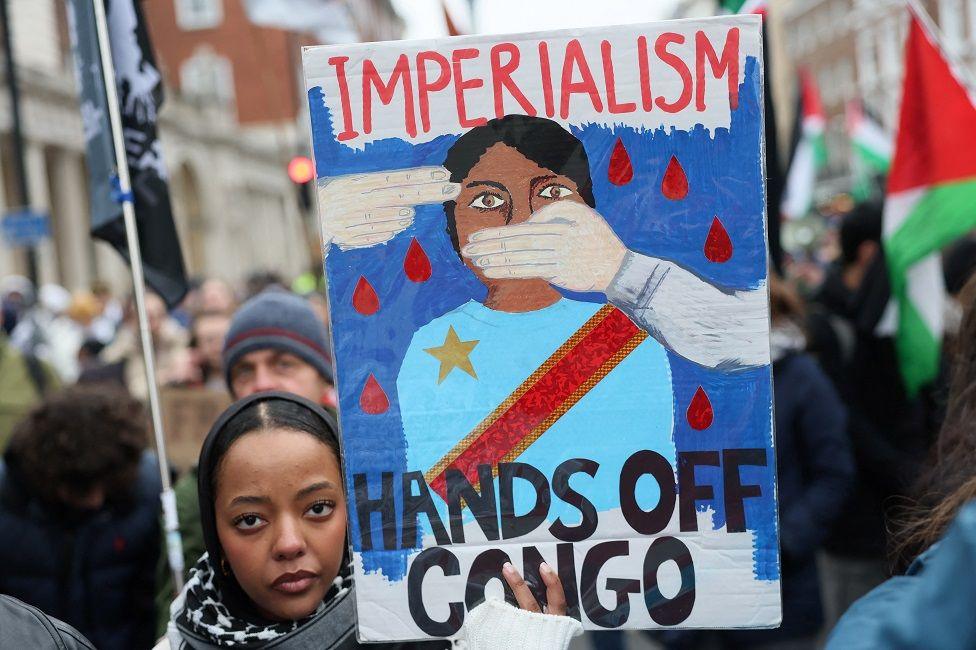 "Hands off Congo" reads the sign being waved by a protester.