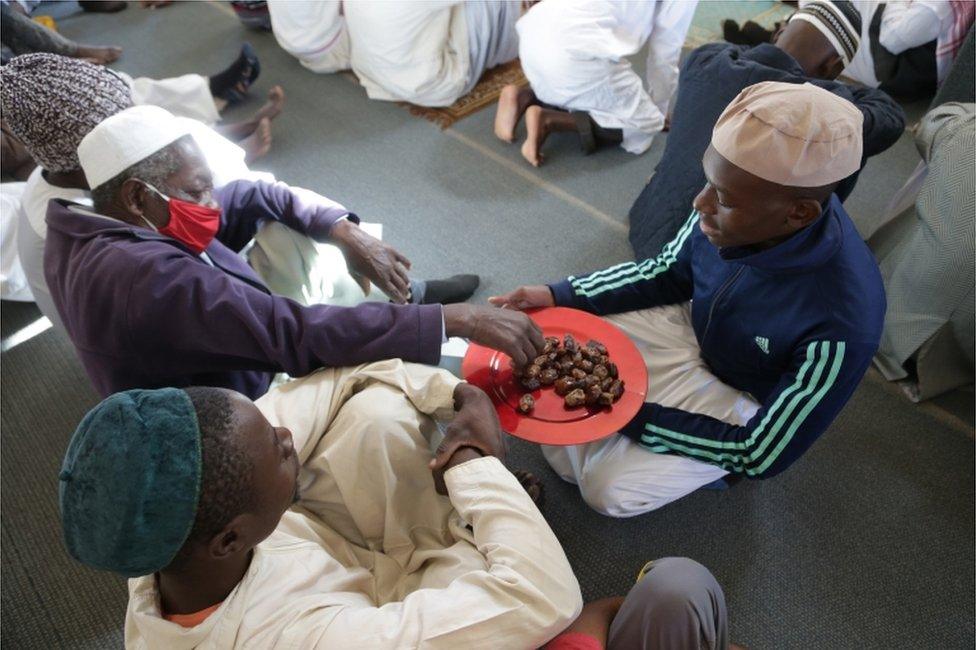 A man hands out dates to worshippers.