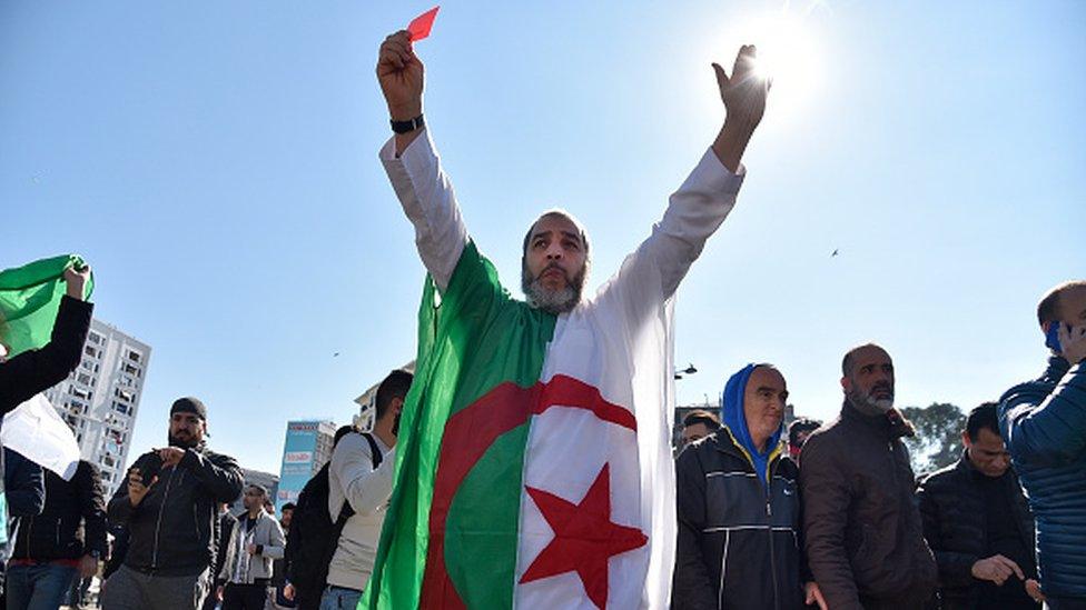 An Algerian protestor wears the national flag at a protest in Algiers