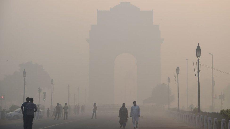 Indian pedestrians walking near the India Gate monument amid heavy smog in New Delhi on October 20, 2017