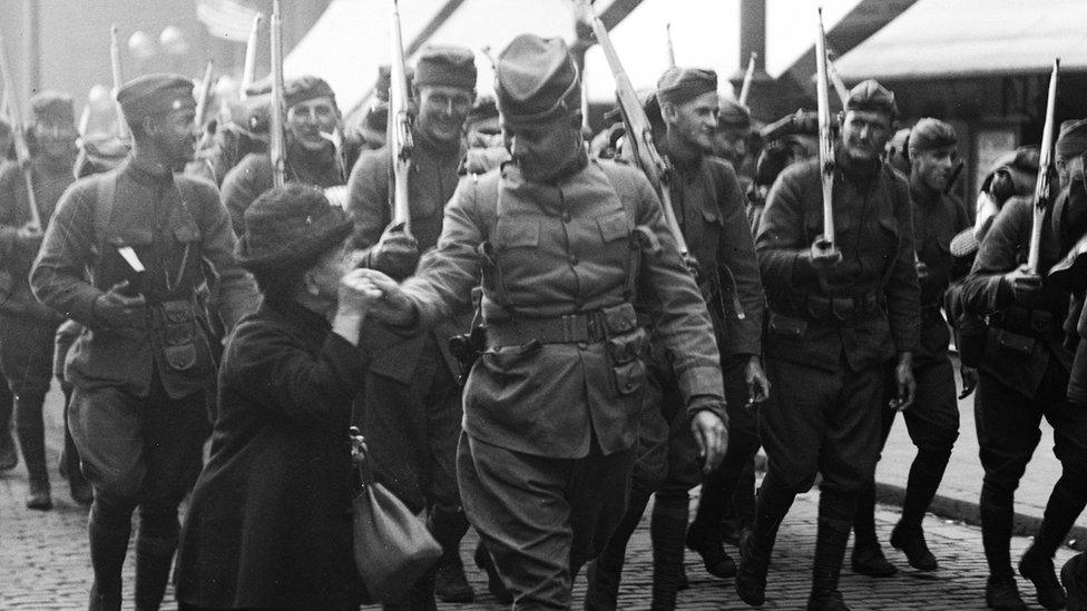 22nd October 1918: A woman kisses the hand of an American soldier marching at the head of his troop as they march through Liverpool after disembarking from their ship.