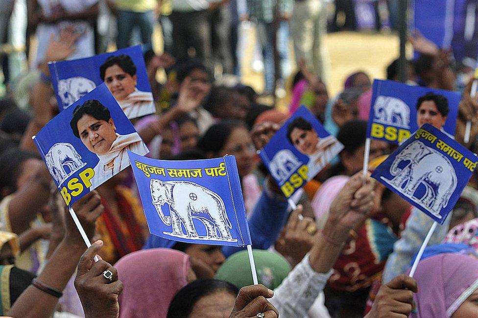 BSP supporters wave party flags at a political rally