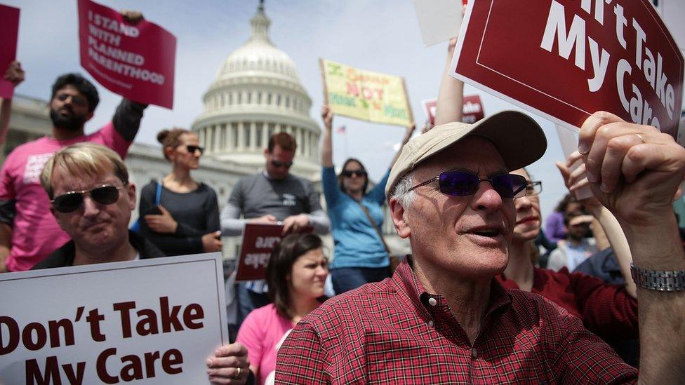 Activists hold signs during a “Stop Trumpcare" rally in front of the Capitol in Washington, DC