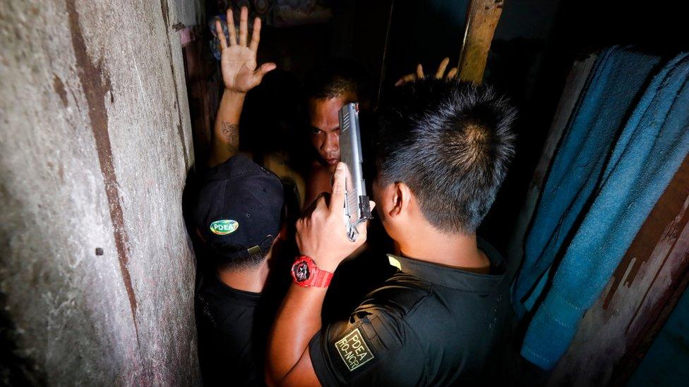 A Filipino who had exhibited suspicious behaviour raises his arms in front of operatives of the Philippine Drug Enforcement Agency (PDEA) during an anti-illegal drugs operation in Makati City, east of Manila, Philippines