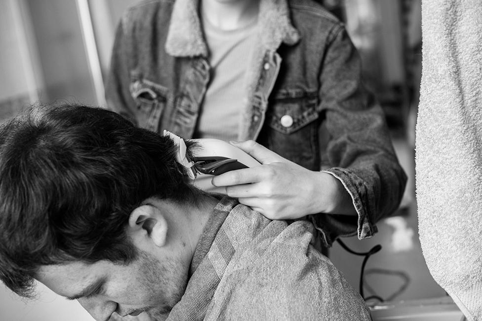 A teenager gets his hair cut at home