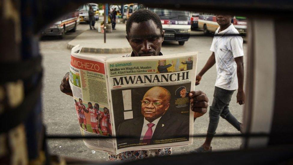 A man reads a newspaper with a headline announcing the death of Tanzania's President John Magufuli in Dar es Salaam, on March 18, 2021. - Tanzania was plunged into mourning on March 18, 2021 over the death of President John Magufuli following weeks of uncertainty over his health, with his swing to authoritarianism leaving a divided legacy.