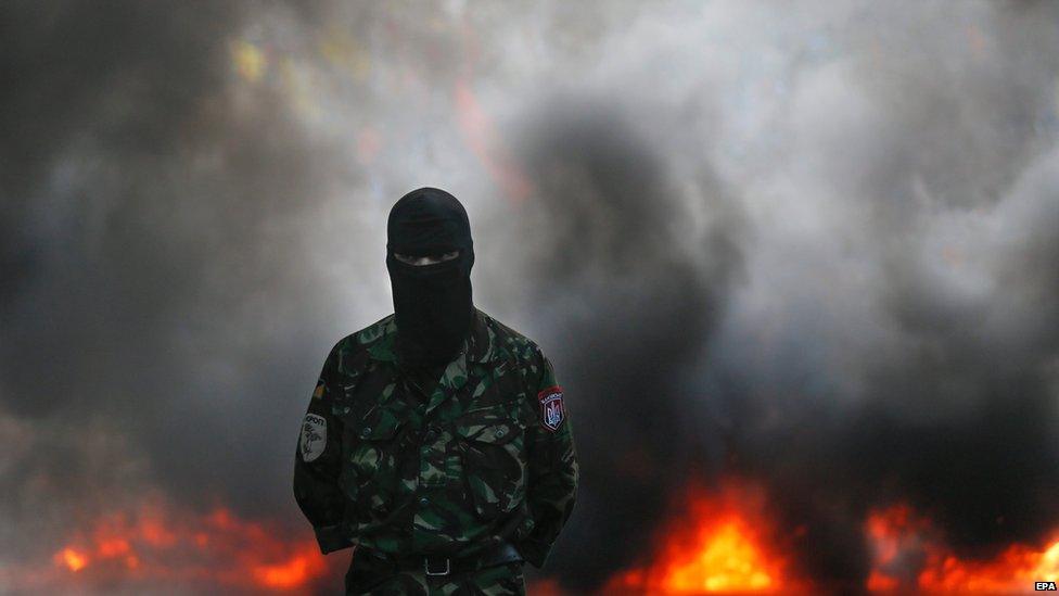 One of the members and supporters of Right Sector and other ultra-right political parties stands in front of burning tires during their protest on Grushevskogo street in Kiev, Ukraine, 3 July 2015