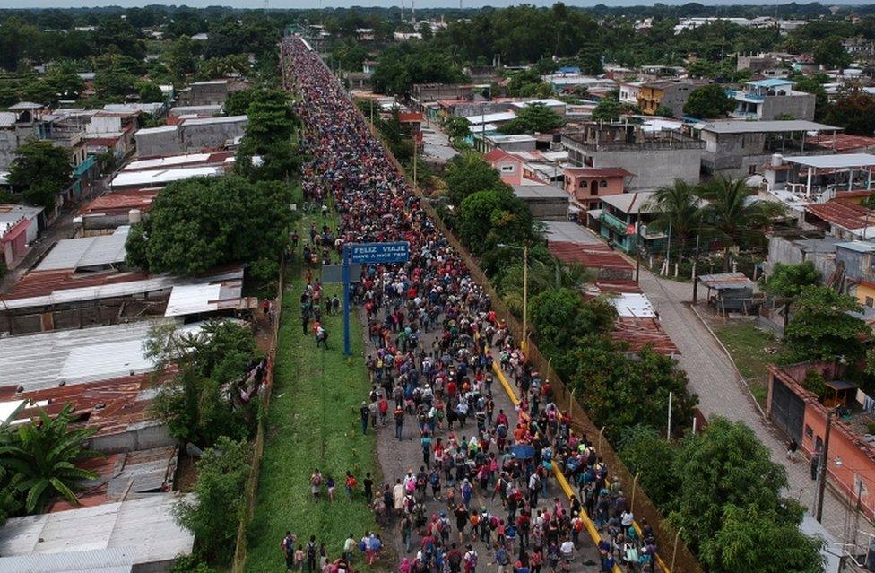 An aerial view of a road filled with migrants stretching back into the distance