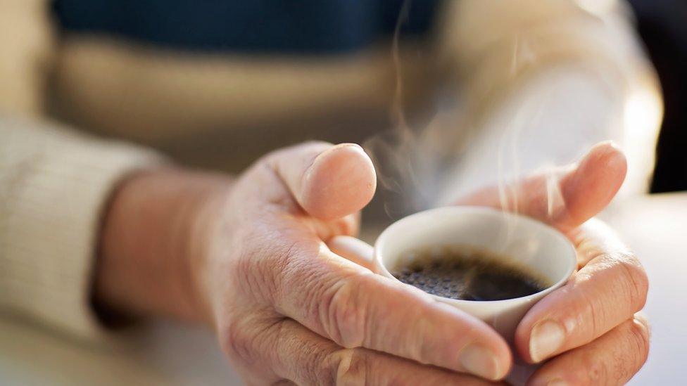 Person's hands holding a hot drink