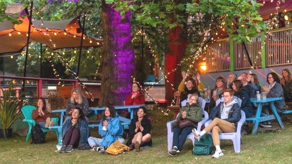 People attending a Book Festival online screening relax in the grounds of the Edinburgh College of Art