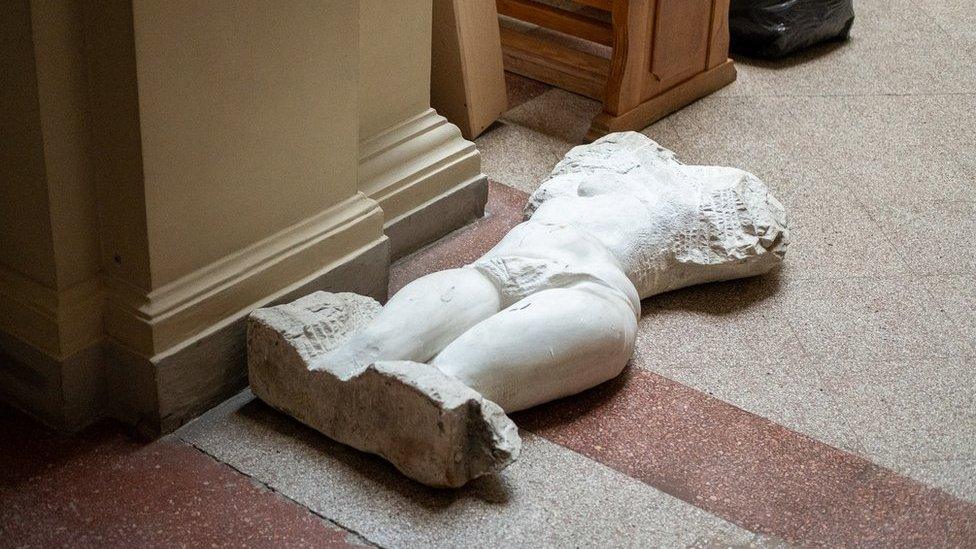 A statue, too heavy to move underground, lies on the floor of the museum's atrium