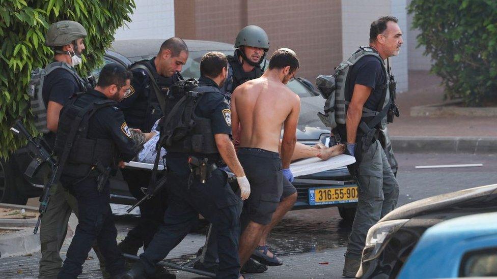 Israelis carry a wounded person on a stretcher in Ashkelon