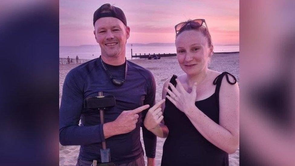 metal detectorist and woman on sandy beach