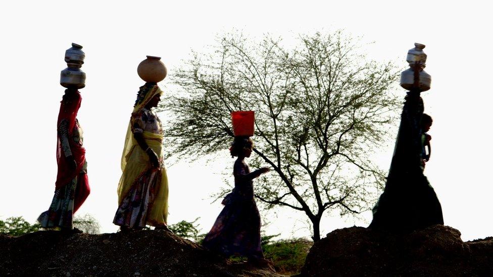 Women walking in line with water pots on their head