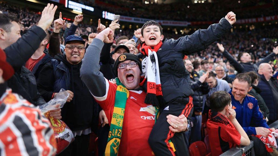 Manchester United fans celebrating in the crowd at Old Trafford after beating Liverpool 4-3 in the FA Cup quarter-final.