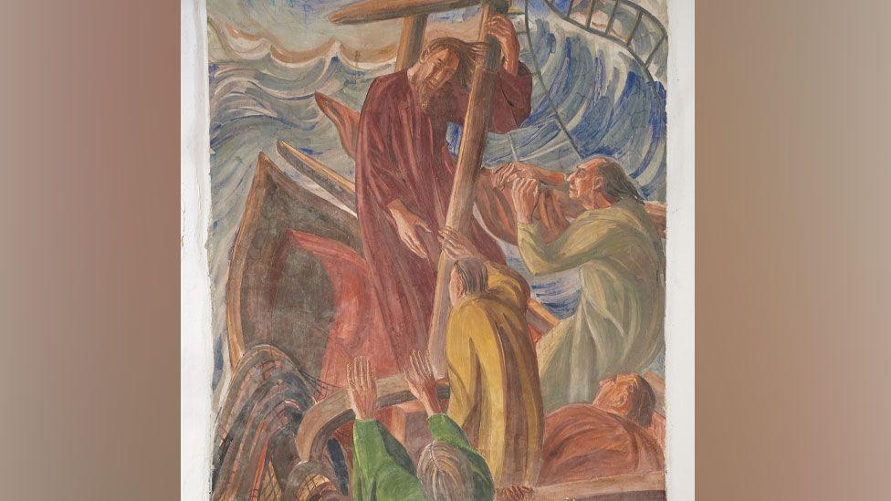 A close-up of a fresco showing Christ stilling the storm. Christ is dressed in a reddish brown robe, his brown beard and hair blowing in the wind, as he stands holding on to a mast in the boat. Four disciples have turned towards him. The boat is being tossed up in a blue, grey and white sea, with large waves.