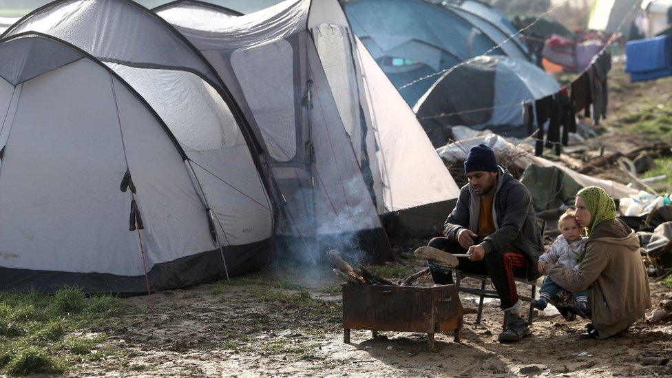 Migrants sit near a fire in a tent camp on 1 March, 2016 near the village of Idomeni as migrants and refugees walk to cross the Greece-Macedonia border.