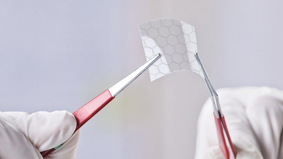 Hands holding a piece of graphene