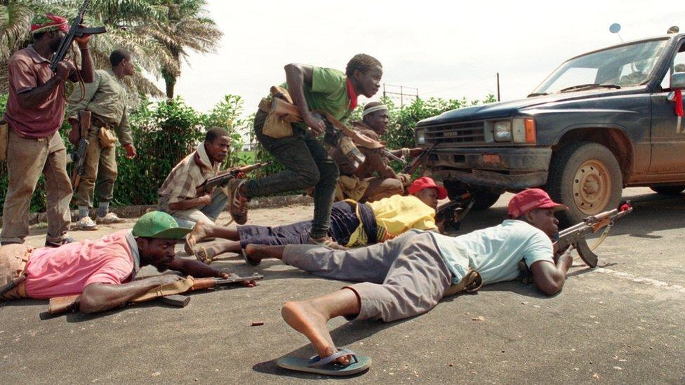 Rebels loyal to warlord Charles Taylor of the National Patriotic Front of Liberia (NPFL) take position behind a truck 30 May 1990