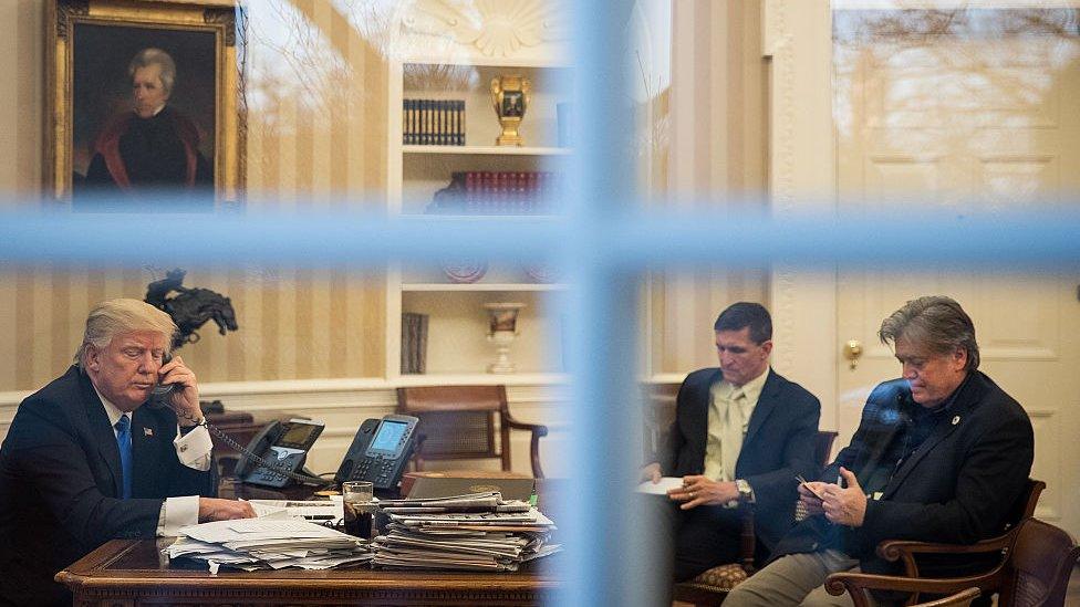 Donald Trump, Michael Flynn and Stephen Bannon sit in the Oval Office.