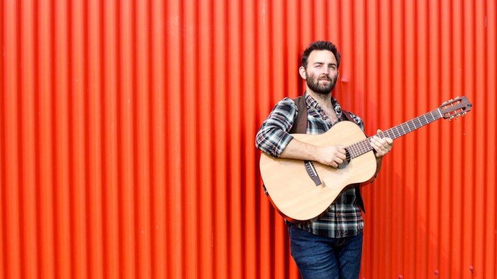 Photo of Sid Goldsmith holding a guitar