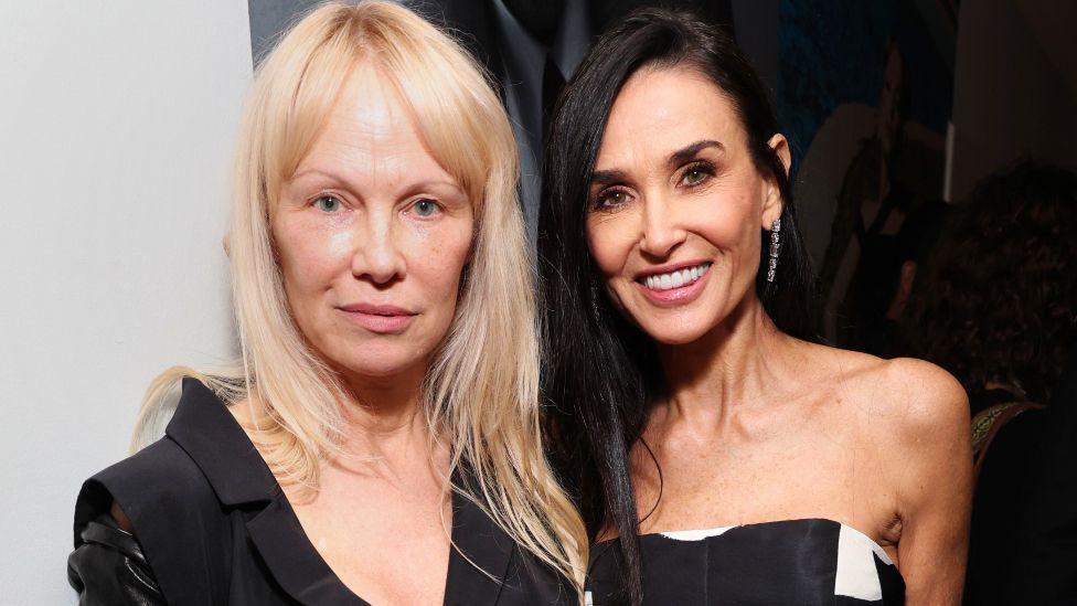 Pamela Anderson and Demi Moore attend W Magazine's Annual Best Performances Party at Chateau Marmont on January 4 2025 in Los Angeles. Anderson is wearing a black jacket and has long blonde hair. Moore has long black hair and is wearing a strapless black and white gown.