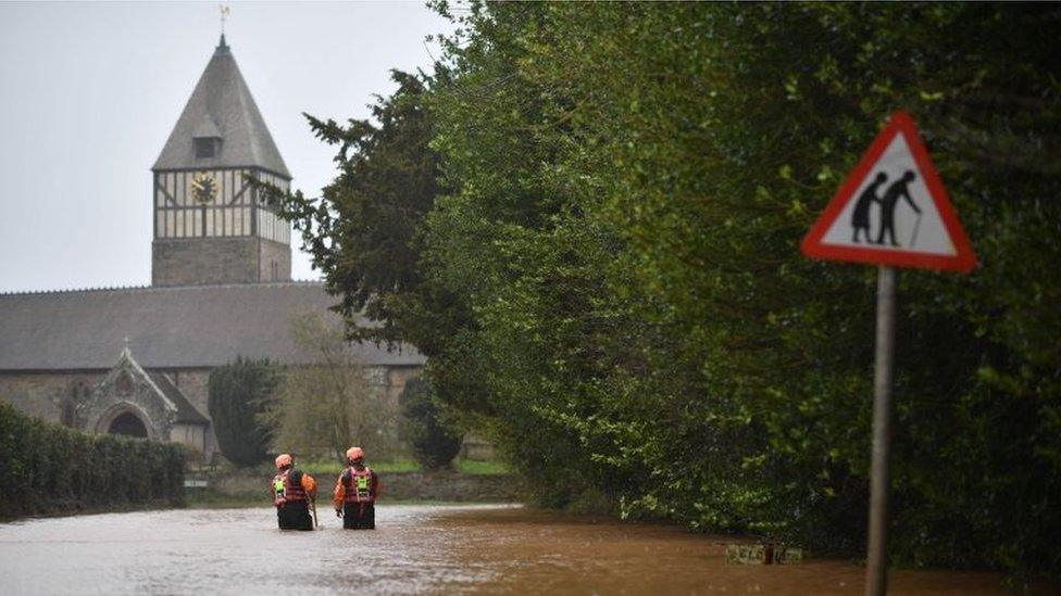 Hereford Fire and Rescue personnel check the depth of flood water as they go along a flooded road in the village of Hampton Bishop in Herefordshire