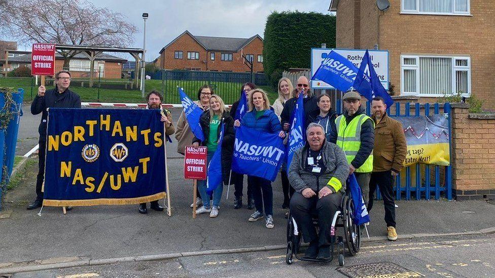 Teachers on the picket line holding up union flags and banners 