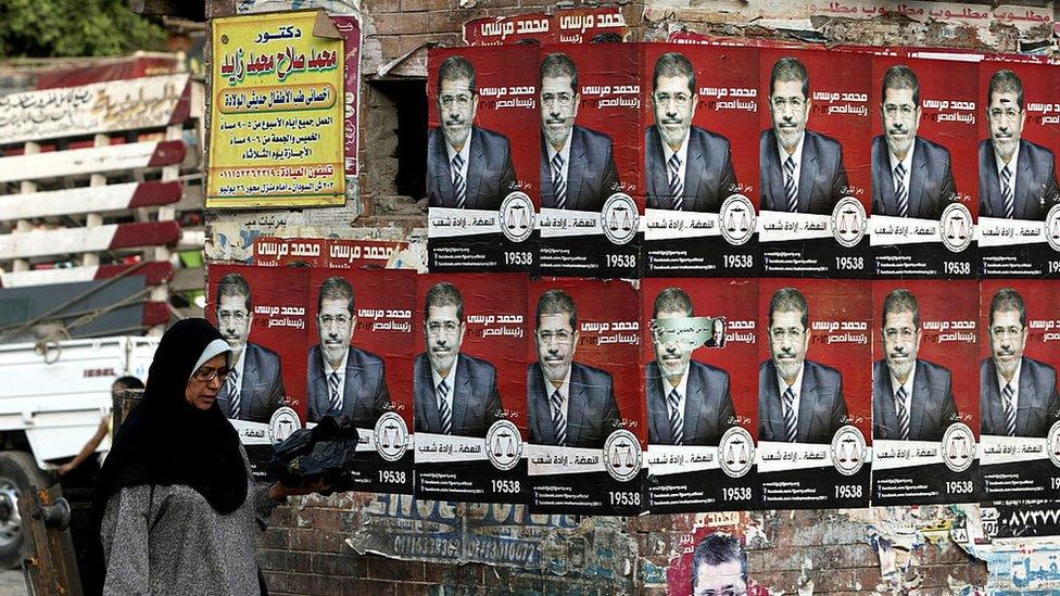 An Egyptian woman walks past election campaign posters for the Muslim Brotherhood's presidential candidate, Mohammed Morsi, in Cairo (21 May 2012)