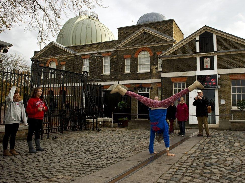 A tourist cartwheels over the meridian line at the Royal Observatory in Greenwich in London on November 3, 2011