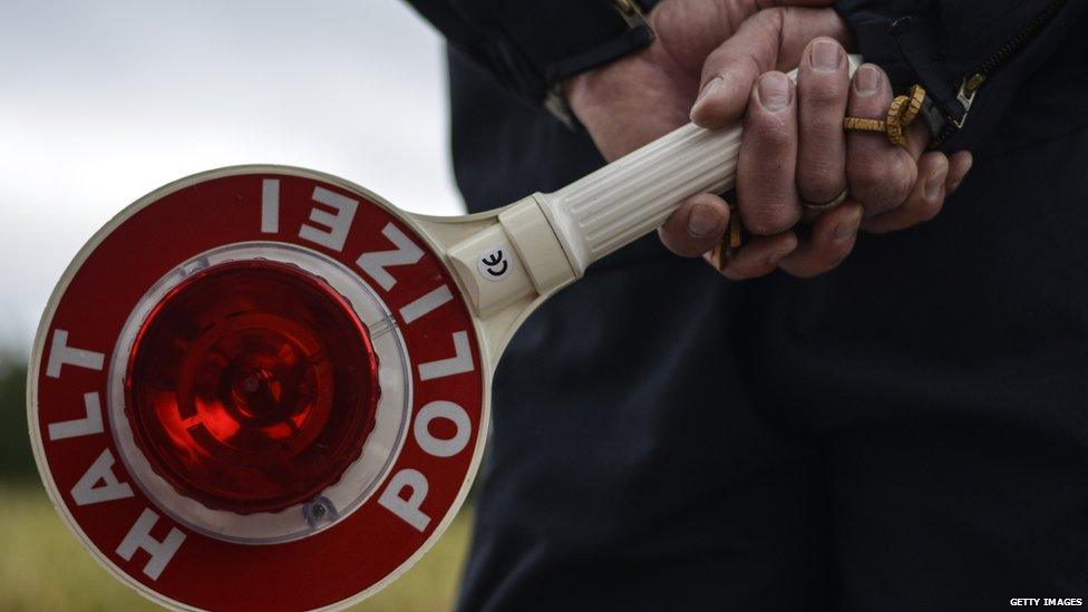 A German police officer holds a stop sign as he observes traffic