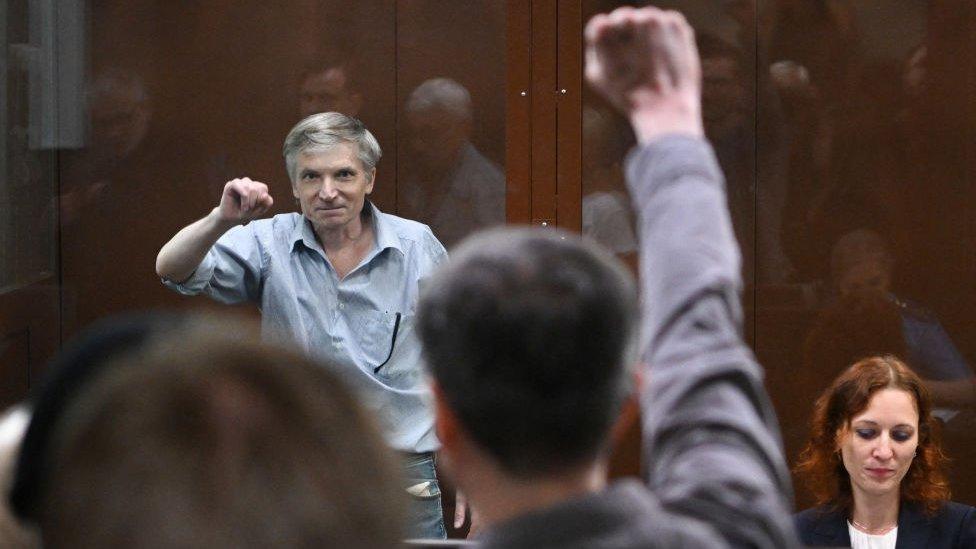 Moscow city deputy Alexei Gorinov, accused of spreading "false information" about the Russian army, gestures inside a glass cell during a hearing in his trial at a courthouse in Moscow on June 21, 2022.