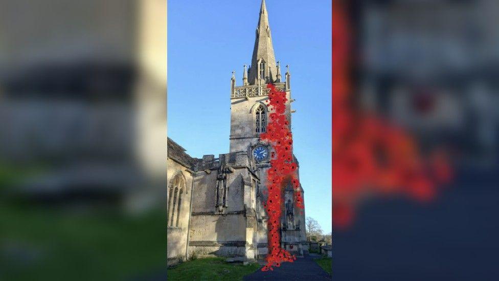 Church tower with short stone spire on top. The tower has a dark blue clock face with gold hands and numbers. An artist has altered the image to show a cascade of poppies draped from the top of the tower, down to the ground and the war memorial below.