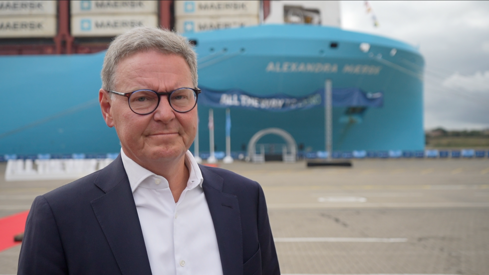 Karsten Kildahl, Chief commercial officer, Maersk, He is in a dark suit with white shirt. He is wearing glasses and standing looking at the camera. The blue of the ship can be seen in the distance.