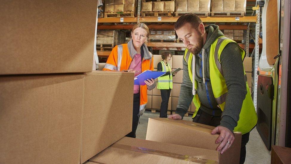 Man taking parcels out of van in warehouse