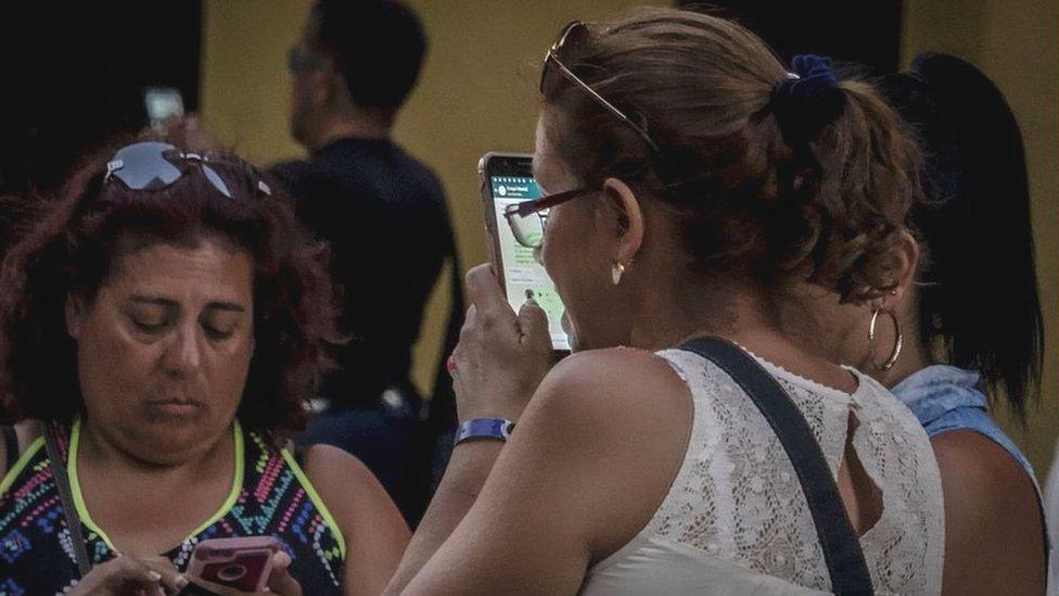 People use public WiFi to connect their devices in a street of Havana