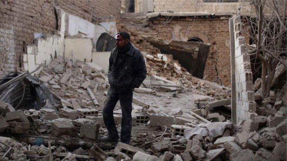 Syrian man standing in rubble