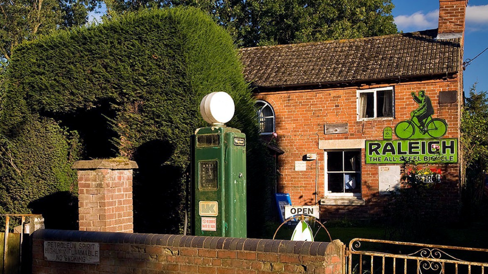 An old fashioned petrol pump outside a house