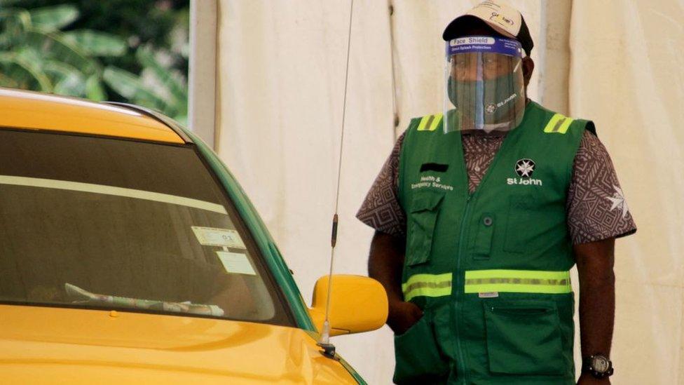 A health worker stands by as people arrive in cars for a covid-19 test