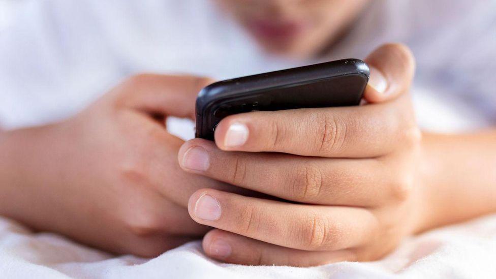 Close up of the hands of a child using a mobile phone