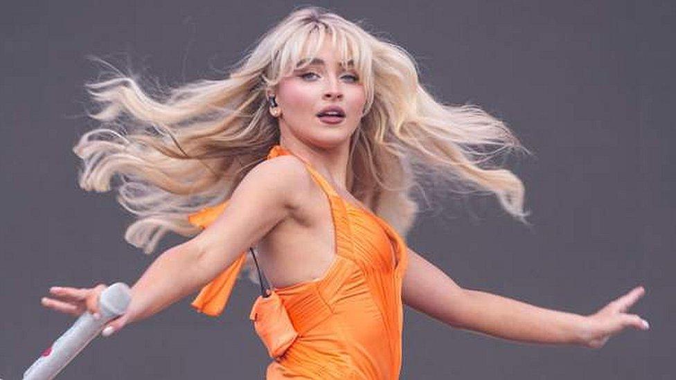 Sabrina Carpenter performs in an orange dress.