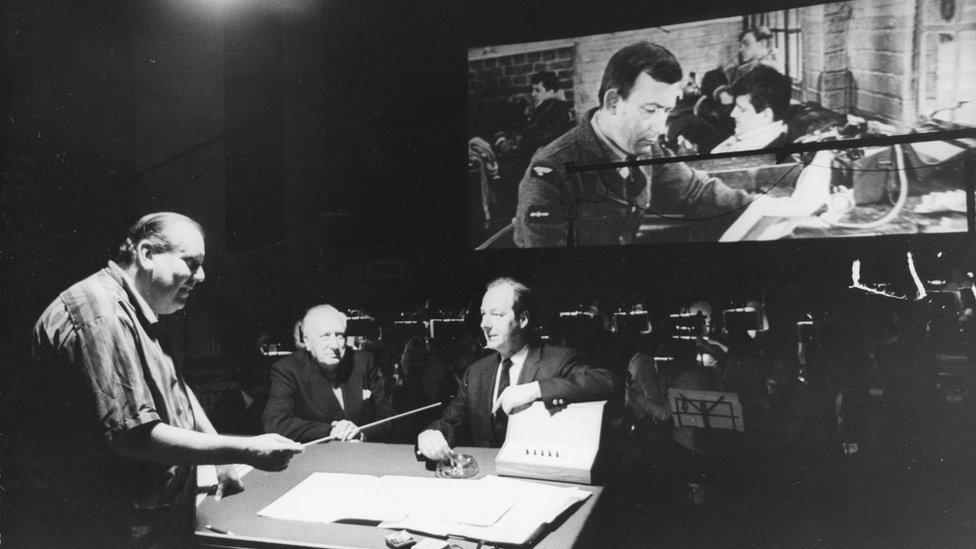 (L-R) conductor Malcolm Arnold, composer Sir William Walton and director Guy Hamilton, with an orchestra and the film playing in the background, Denham Studios, Bucks, April 8th 1969.