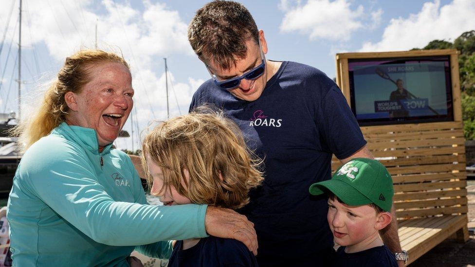 Leanne embracing her husband and two sons in Antigua.