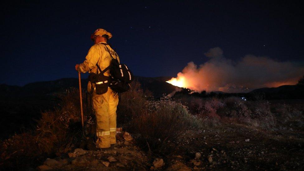 A firefighter battles the "Apple Fire" near Beaumont in Riverside County, California