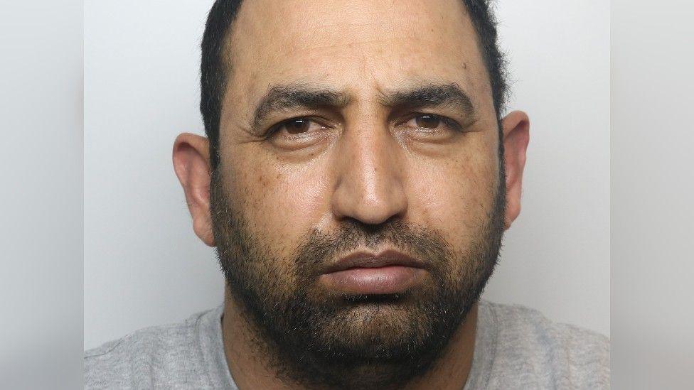 A police photo of Ifzal Hussain, a man wearing a grey t-shirt.