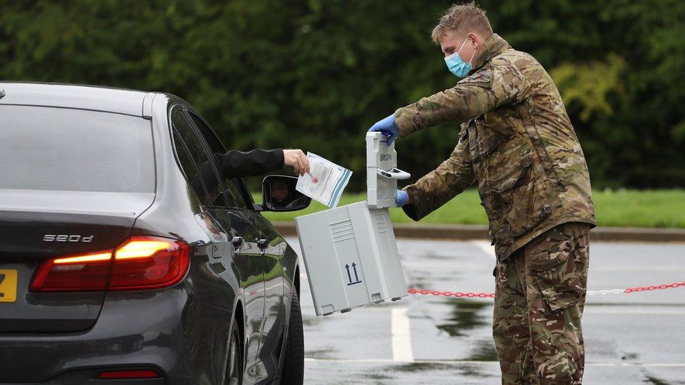 A soldier collects a test from someone through their car window