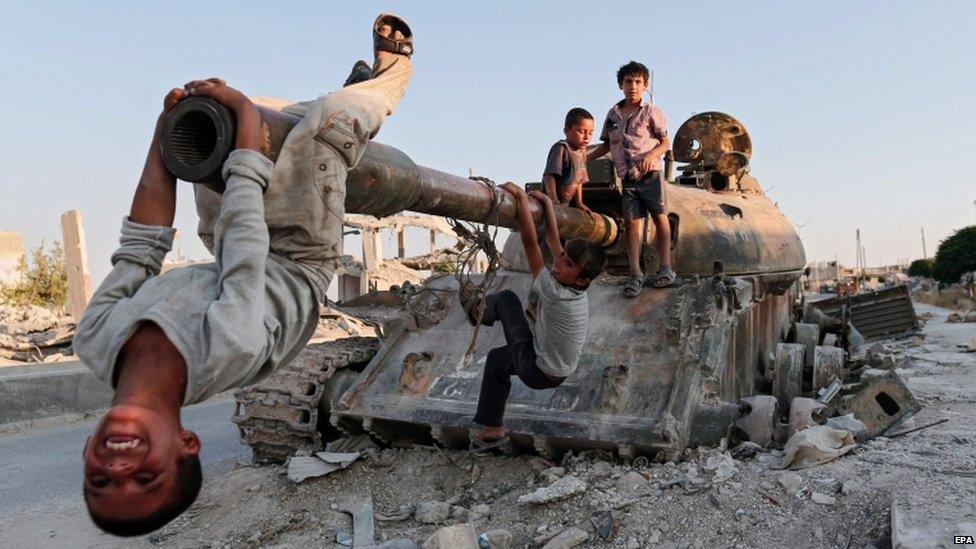 Syrian children play on a destroyed tank in south of Kobane in Syria, 22 June 2015.