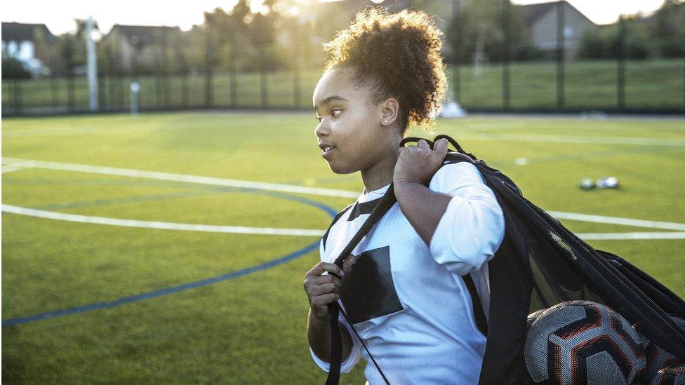 girl-holding-bag-with-footballs.