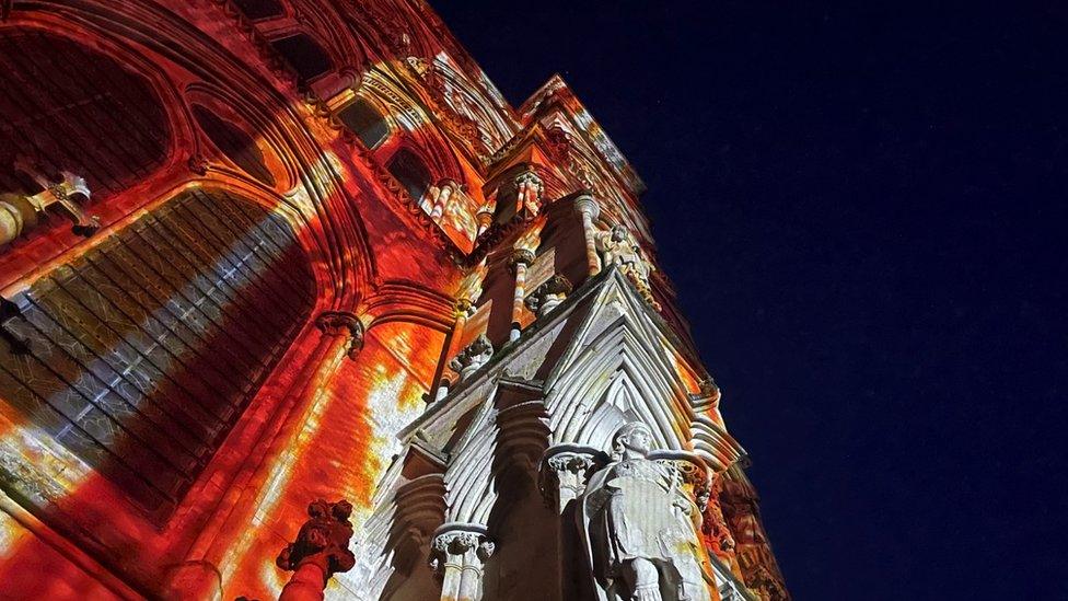 Image of the Sarum Lights exhibition at Salisbury Cathedral. The building has red lights projected onto it.