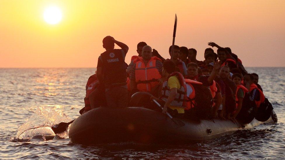 Migrants and refugees paddling a rubber dinghy close to the Greek coast